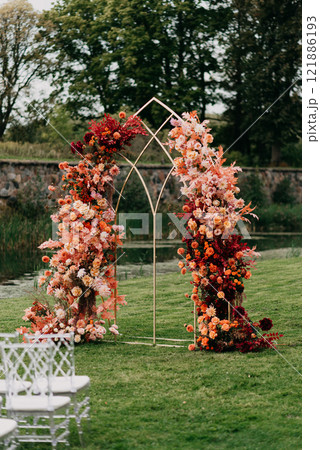 A flowerdecorated wedding arch stands in a lush green field A flowerdecorated wedding arch stands in a lush green field 121886193