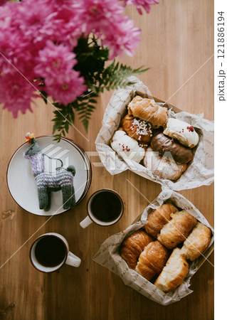 A wooden table with a basket of donuts and two coffee cups 121886194