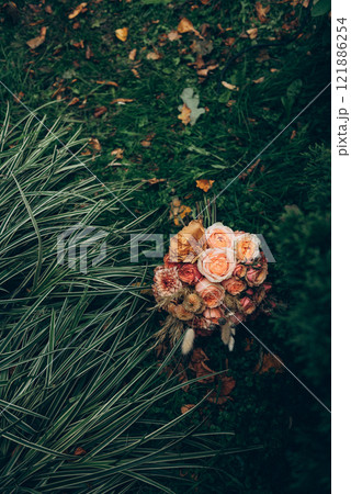 A beautiful bouquet of vibrant flowers is sitting in the lush grass 121886254