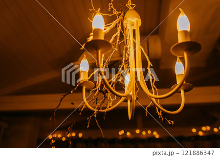 A stunning chandelier with candles, enhancing a dimly lit room A stunning chandelier with candles, enhancing a dimly lit room 121886347