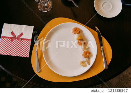 There is a plate that has shrimp on it placed on a bright yellow place mat 121886367