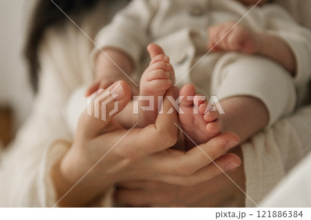 A woman is gently holding a newborn baby securely in her arms 121886384