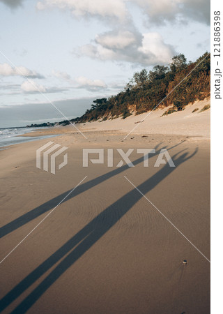 A persons shadow is distinctly cast on a beautiful sandy beach during the day 121886398