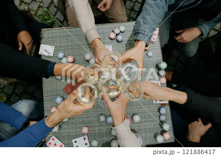 People are sitting around a table toasting with wine glasses People are sitting around a table toasting with wine glasses 121886417