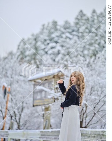 雪の中で散歩する女性 121886677