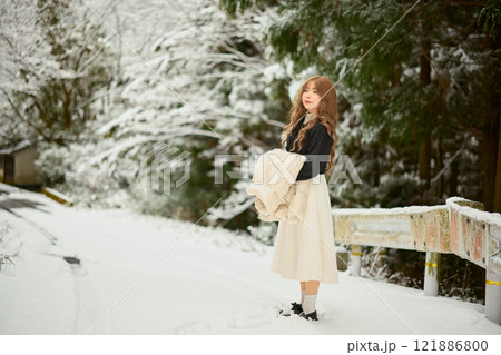 雪の中で散歩する女性 121886800