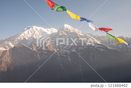 Prayer flags blowing by the wind with View of Mt.Annapurna South (7,219 m) and Mt.Hiunchuli (6,441 m) before sunrise seen from Mardi Himal view point in the Annapurna region of Nepal. Prayer flags blowing by the wind with View of Mt.Annapurna South (7,219 m) and Mt.Hiunchuli (6,441 m) before sunrise seen from Mardi Himal view point in the Annapurna region of Nepal. 121888402