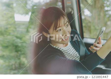 スマホ地図アプリでルート検索する助手席の女性 121891447