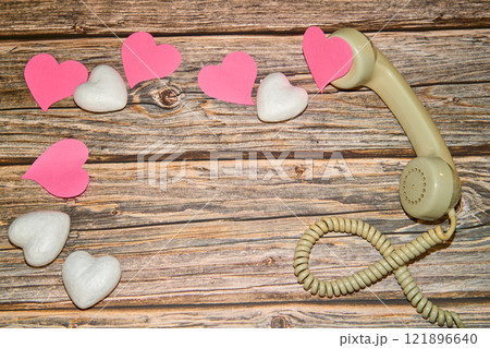old cable headset with a pile of pink and white hearts on a wooden table 121896640