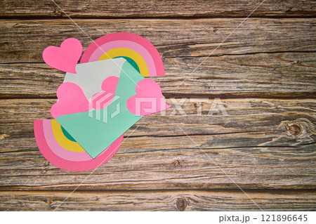 Light green envelope with pink hearts spilling out, a rainbow on a table Light green envelope with pink hearts spilling out, a rainbow on a table 121896645