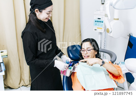 Patient with dentist choosing dental braces, Dentist with patient choosing metal braces, Patient with dentist choosing rubber band 121897745