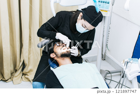 Dentist performing dental checkup, dentist checking braces to patient, patient checked by dentist 121897747
