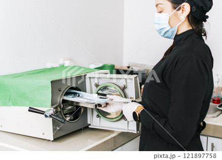 Dentist with a dental sterilizer, A dentist sterilizing his tools, A dentist with a dental autoclave, Close up of a dentist with a steam sterilizer Dentist with a dental sterilizer, A dentist sterilizing his tools, A dentist with a dental autoclave, Close up of a dentist with a steam sterilizer 121897758