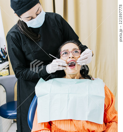 Dentist performing dental checkup, Patient checked by dentist, close up of dentist with patient, dentist performing root canal treatment on patient 121897778