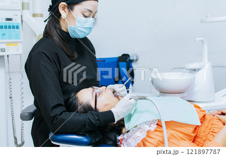 The stomatologist cleaning a patient's teeth, a dentist cleaning a patient's mouth, a dentist cleaning a patient's caries, a dentist cleaning a patient's mouth The stomatologist cleaning a patient's teeth, a dentist cleaning a patient's mouth, a dentist cleaning a patient's caries, a dentist cleaning a patient's mouth 121897787