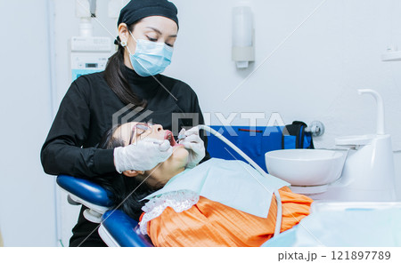 The stomatologist cleaning a patient's teeth, a dentist cleaning a patient's mouth, a dentist cleaning a patient's caries, a dentist cleaning a patient's mouth 121897789