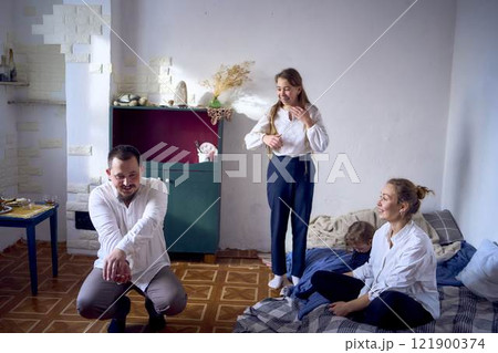 family with toddler and teenager playing games, laughing, clapping and celebrating a small family party 121900374