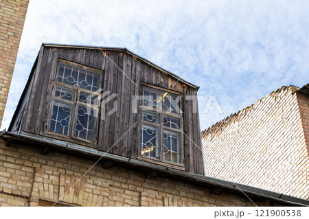 Old wooden attic above the roof of the house. Attic with windows 121900538