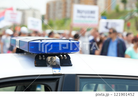 Police car flashing lights in focus, blurred protesters in the background Police car flashing lights in focus, blurred protesters in the background 121901452