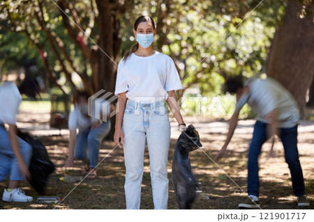 Volunteer help of covid cleaning community group working together outdoors. Portrait of a young female worker doing nature and forest clean up of plastic garbage outside to be green for the future 121901717
