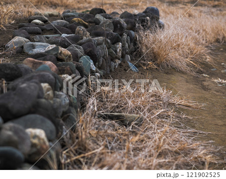 枯れ草と石積みが織りなす冬の田舎風景―ノスタルジックな雰囲気を演出する素朴な自然写真 121902525