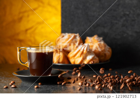 Black coffee in glass cup and coffee beans in motion on a black table. 121902713