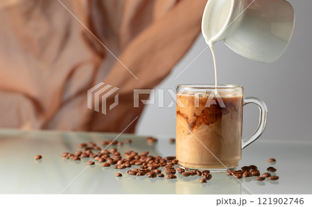 Pouring milk in black coffee. Pouring milk in black coffee. 121902746