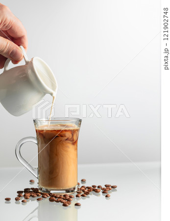 Barista pours cream into a glass of coffee. Barista pours cream into a glass of coffee. 121902748
