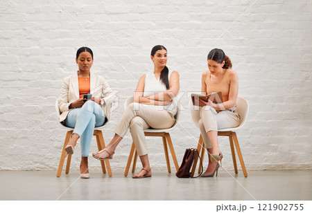 Employment, hiring and recruitment with business women waiting for an interview with human resources and sitting on chairs. Young female shortlist candidates doing research and preparing for meeting 121902755