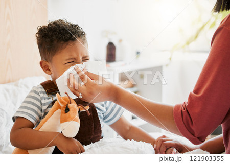 Flu, sick or cold child with parent sneezing, blowing and wiping runny nose while ill with covid virus, sinus and allergy symptoms in bed at home. Mother caring for stuffy and congested little son 121903355