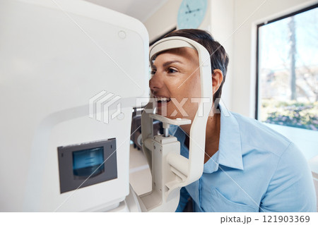An eye test, exam or screening for vision and eyesight at the optometrist or optician with a young woman. Testing her sight with an automated refractor for prescription glasses or contact lenses An eye test, exam or screening for vision and eyesight at the optometrist or optician with a young woman. Testing her sight with an automated refractor for prescription glasses or contact lenses 121903369