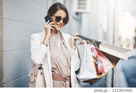 Trendy, stylish and fashionable woman shopping, purchasing and buying clothes in city, town and downtown. Elegant lady talking on phone with gift bags, going on spending spree or doing retail therapy 121903485