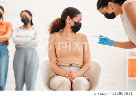 A covid vaccine of a young woman getting vaccinated for work in the office. Young wearing a mask female getting an injection or treatment to prevent the spread of coronavirus at the workplace 121903611