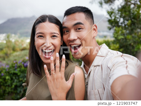 Engagement, ring and celebration with a young couple announcing their happy news and special occasion. Closeup portrait of a man and woman taking a selfie after getting engaged to be married outside Engagement, ring and celebration with a young couple announcing their happy news and special occasion. Closeup portrait of a man and woman taking a selfie after getting engaged to be married outside 121903747