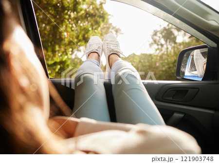 Relaxed, content and happy woman relax while enjoying the sunny morning in a car. Back view of female with feet out her window taking a break from driving sitting and enjoying the summer sunshine day Relaxed, content and happy woman relax while enjoying the sunny morning in a car. Back view of female with feet out her window taking a break from driving sitting and enjoying the summer sunshine day 121903748