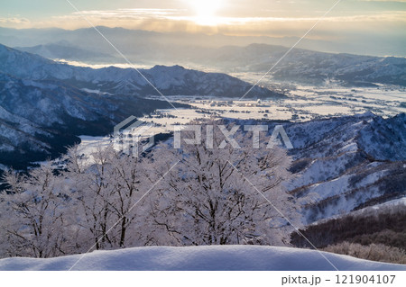 スキー場山頂の展望台から見る夕日と魚沼平野周辺の山並み 121904107