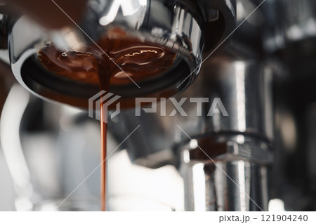 Extracting espresso with naked portafilter closeup Extracting espresso with naked portafilter closeup 121904240