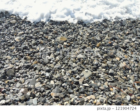 beautiful background texture with round gray sea pebbles and foamy wave, wet pebbles on the shore and sea tide with white foam as natural graphic design blank 121904724