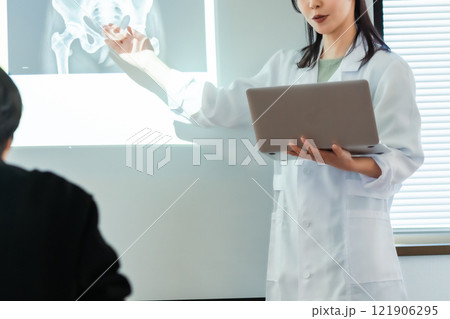 メディカルカンファレンスでプレゼンするドクター　顔無し 121906295
