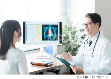 女性患者に丁寧に対応するミドルの男性医師 121906305