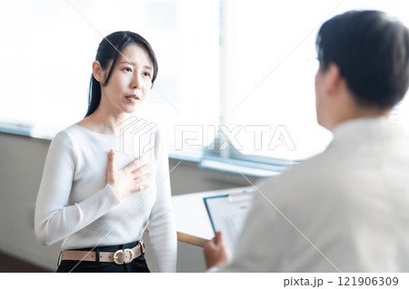 ドクターに症状を説明する女性患者 121906309