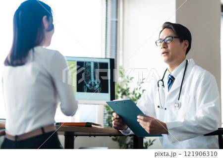 女性患者に丁寧に対応するミドルの男性医師 121906310