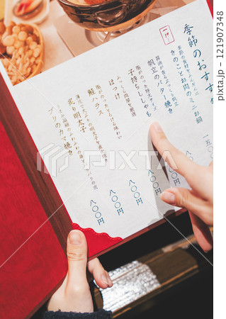 メニューを見て選ぶ女性客の手【撮影協力・海鮮居酒屋　魚魯こ】 121907348