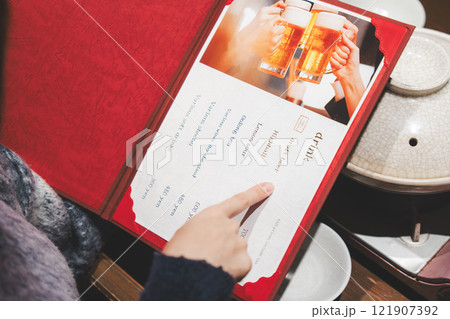 メニューを見て選ぶ女性客の手【撮影協力・海鮮居酒屋　魚魯こ】 121907392
