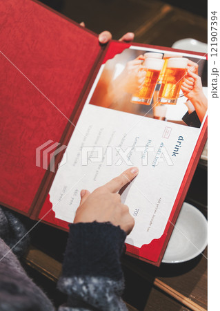 メニューを見て選ぶ女性客の手【撮影協力・海鮮居酒屋　魚魯こ】 121907394