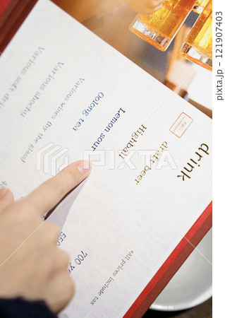 メニューを見て選ぶ女性客の手【撮影協力・海鮮居酒屋　魚魯こ】 121907403