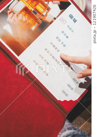 メニューを見て選ぶ女性客の手【撮影協力・海鮮居酒屋　魚魯こ】 121907426