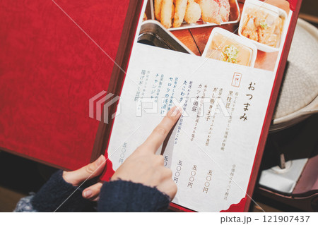 メニューを見て選ぶ女性客の手【撮影協力・海鮮居酒屋 魚魯こ】 メニューを見て選ぶ女性客の手【撮影協力・海鮮居酒屋 魚魯こ】 121907437