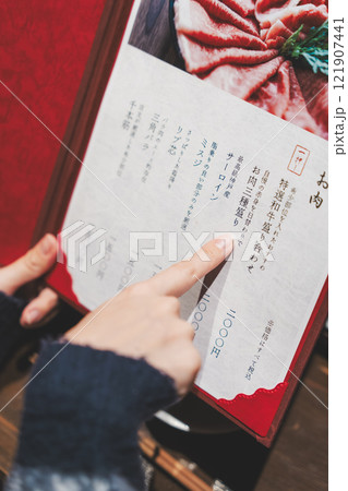 メニューを見て選ぶ女性客の手【撮影協力・海鮮居酒屋 魚魯こ】 メニューを見て選ぶ女性客の手【撮影協力・海鮮居酒屋 魚魯こ】 121907441