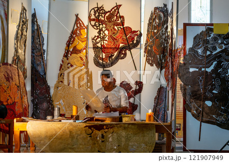 Wide shot of Asian senior man hold paper as sketch pad to create grand shadow play craft in area of workplace and he look happy and pround for his work. 121907949